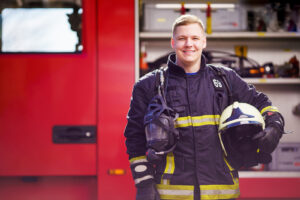 Photo of happy male firefighter with helmet in his hands against