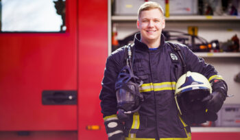 Photo of happy male firefighter with helmet in his hands against