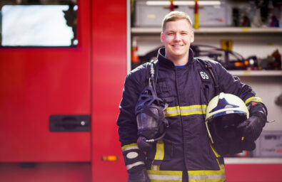 Photo of happy male firefighter with helmet in his hands against